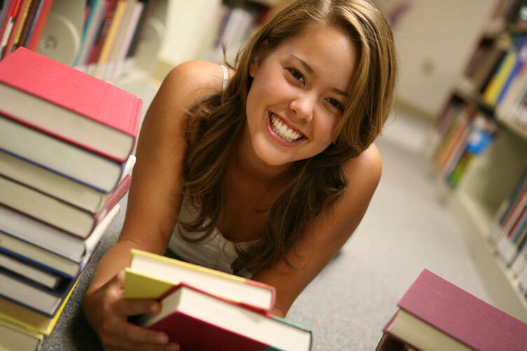 A girl laying on the floor surrounded by a stack of books, displaying visible signs of school stress.